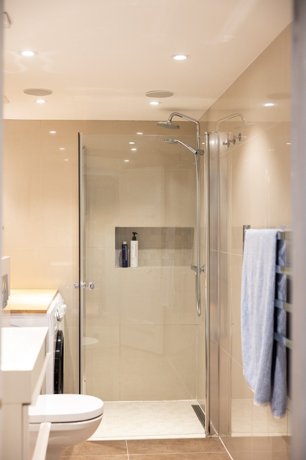 Badet er utstyrt med servantinnredning, speil, dusjhjørne med glassdører og opplegg til vaskemaskin og tørketrommel. Galleribilde