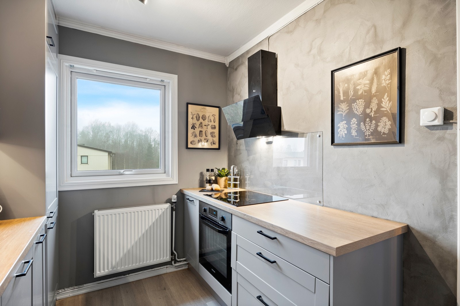 Kjøkkenet ligger praktisk tilbaketrukket og er utstyrt med integrerte hvitevarer som induksjonstopp, stekeovn, oppvaskmaskin og kjøleskap med frysedel. Galleribilde