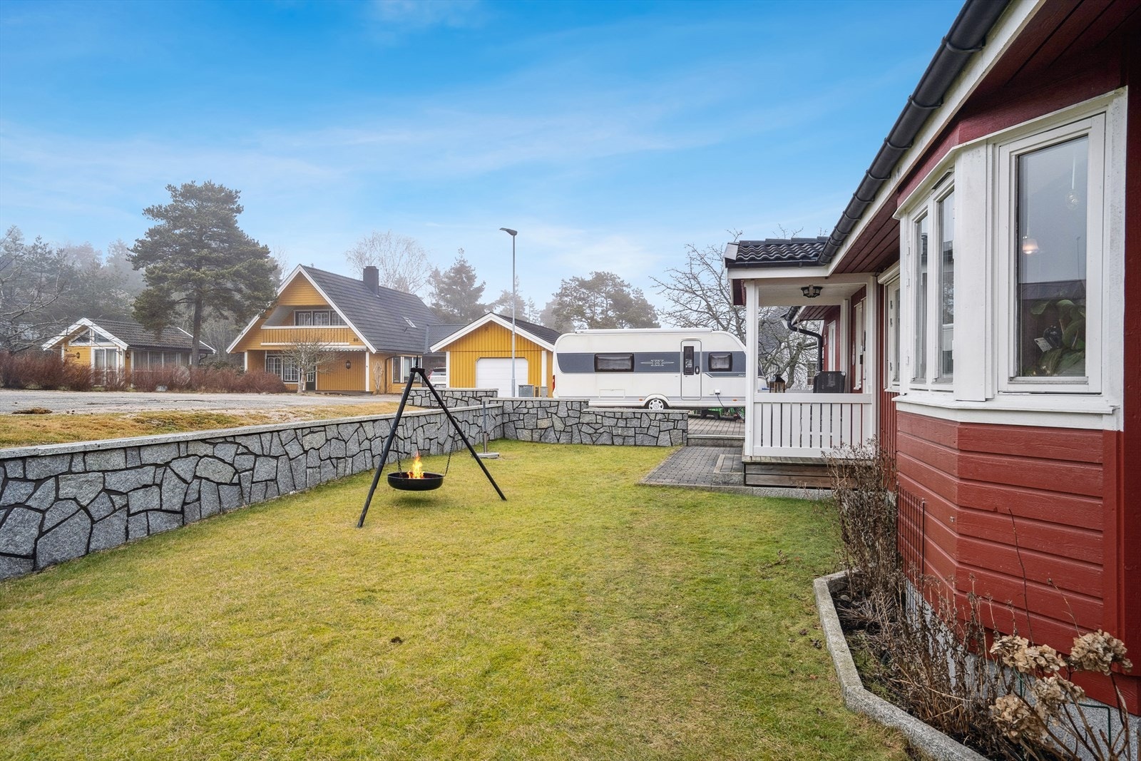 Foran boligen har du en en flat gressplen som er rammet inn med en støttemur. Galleribilde