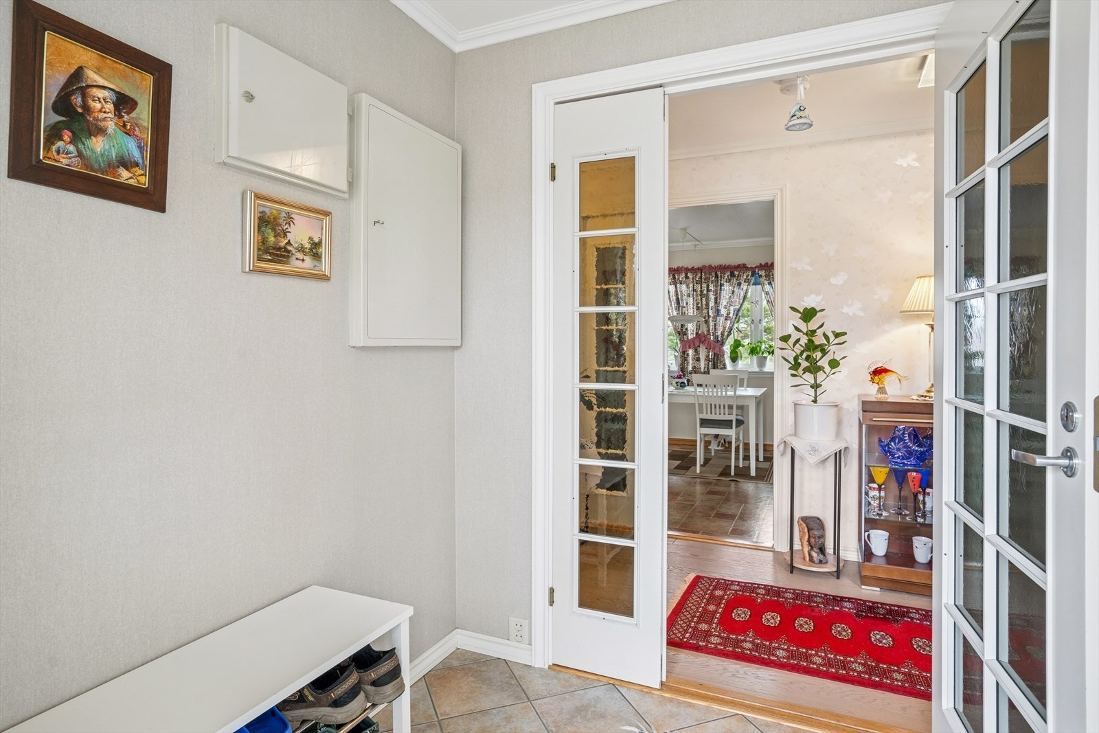 Du ønskes velkommen inn i en lys entre med fliser på gulvet og glassdører videre inn i boligens gang. Galleribilde