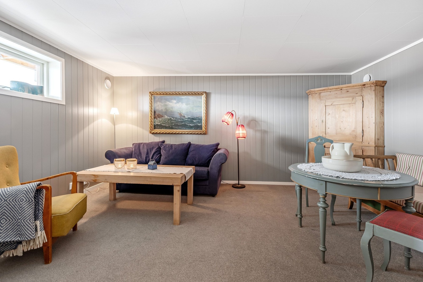 Romslig kjellerstue med teppebelagt gulv, lysegrå veggplater. God plass for møblement. Galleribilde