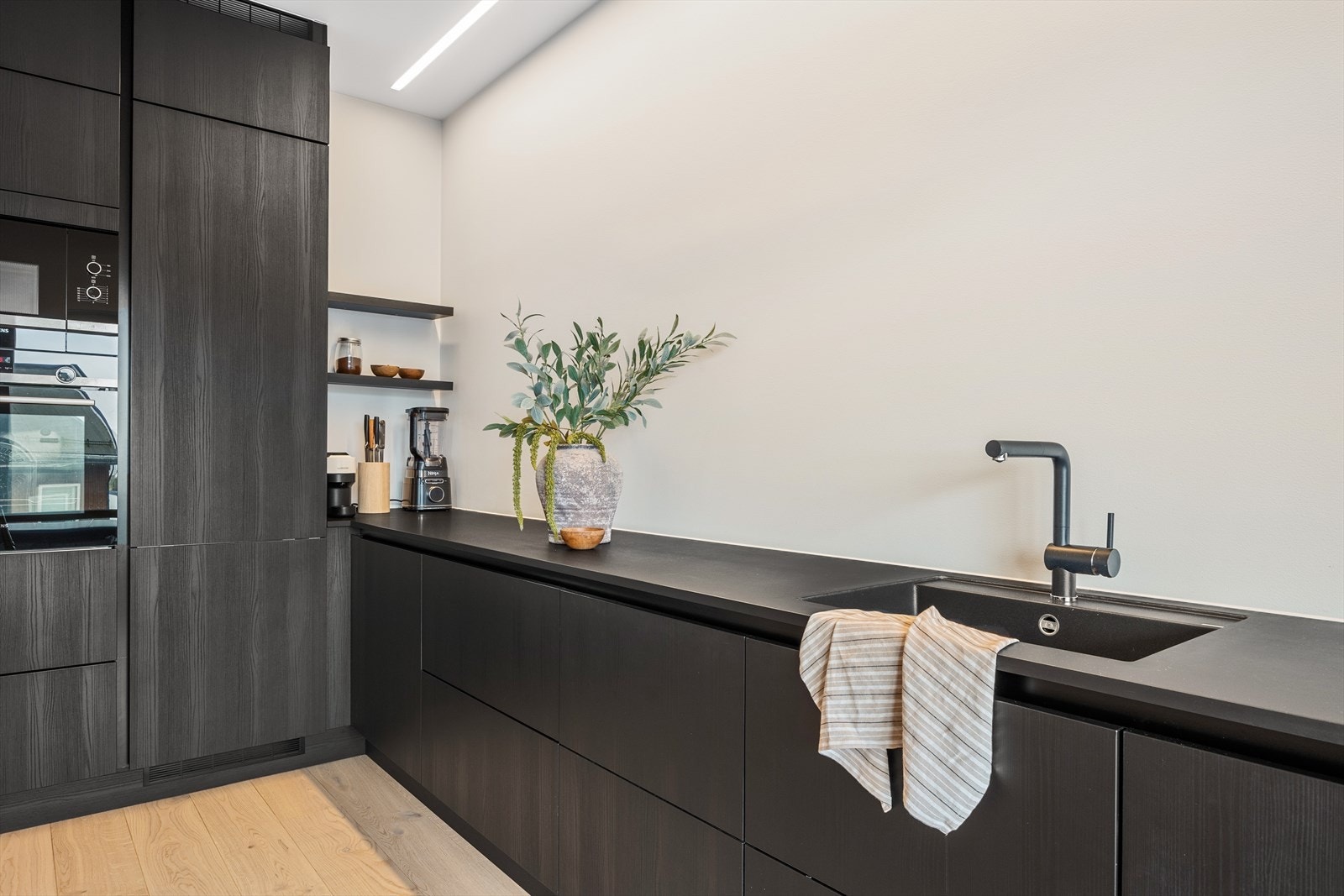 Meget stilren benkeplate med nedfelt sort vaskekum og med sort blandebatteri. Galleribilde