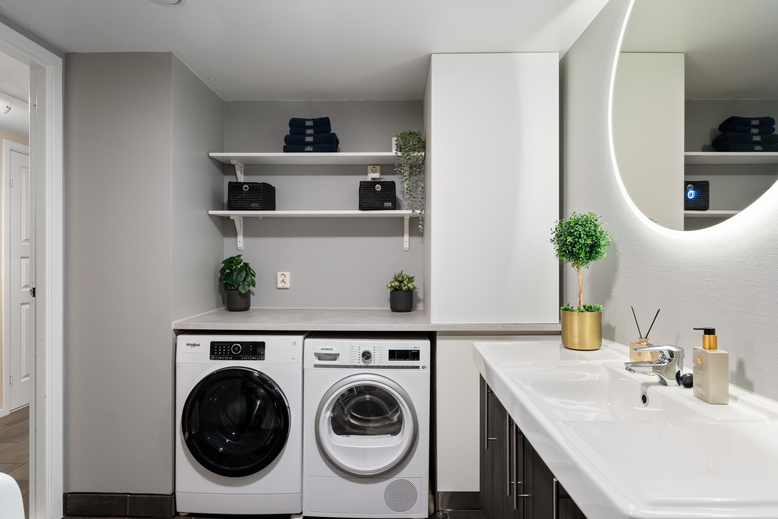 Her er det plass og opplegg for vaskemaskin og tørketrommel. Disse har fått sin naturlige plass under en praktisk benkeplate, som sammen med høyskap og hyller er fra 2021. Galleribilde
