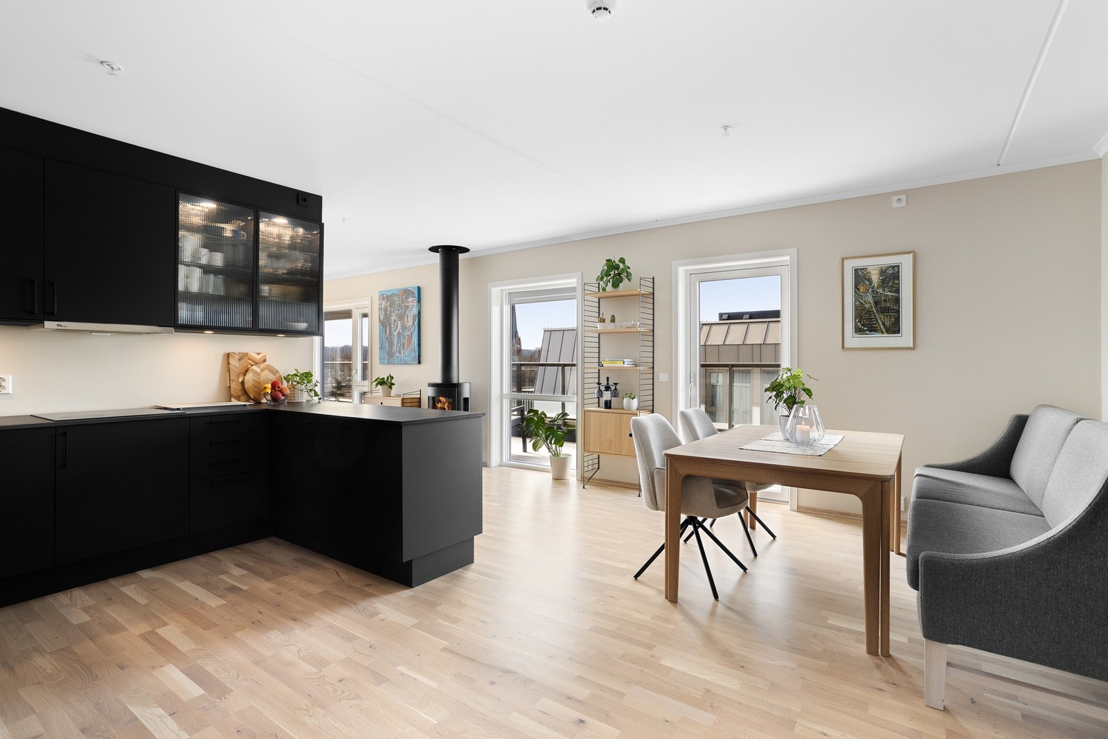 Kjøkken med svart innredning fra HTH og åpen løsning mot spiseplass. Store vinduer gir godt med naturlig lys. Galleribilde