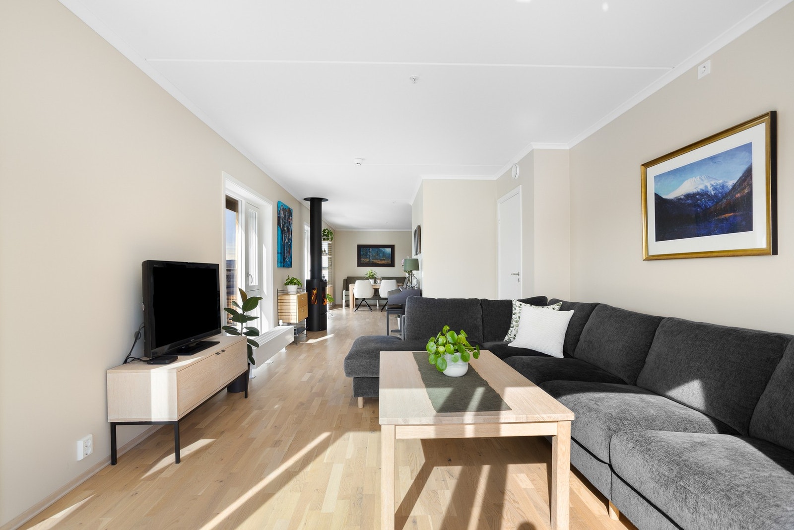 Lyst og romslig stueområde med peis og sittegruppe. Store vinduer gir mye naturlig lys. Galleribilde