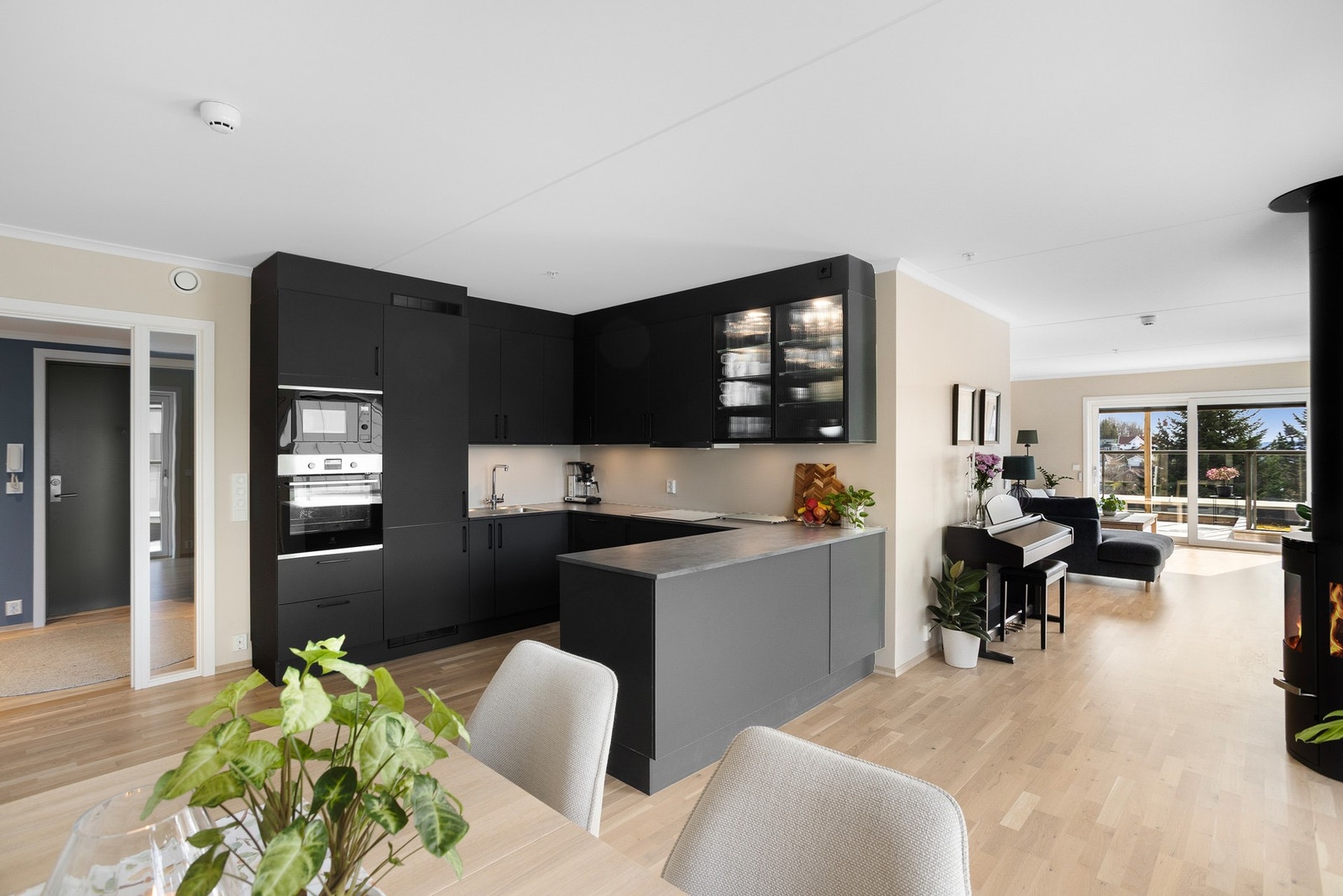 Moderne kjøkken med integrerte hvitevarer og åpen løsning mot stue. Store vinduer gir godt med naturlig lys. Galleribilde