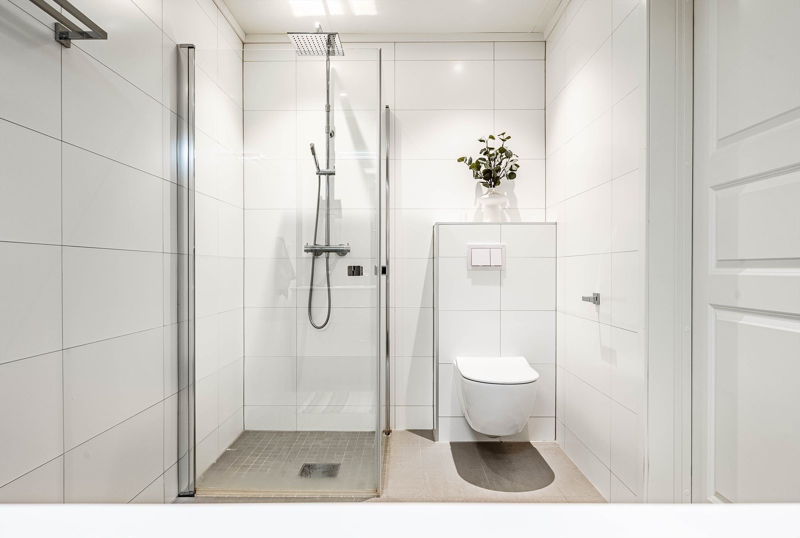 Flott bad med flislagt gulv. Badet har vegghengt toalett, hjørnedusj og servant. Galleribilde