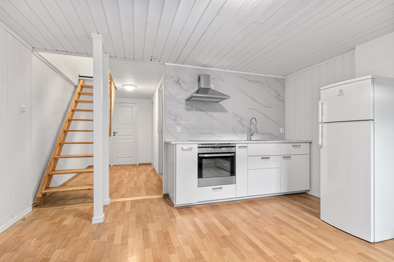 Kjellerkjøkken med moderne hvitevarer og tretrapp. Galleribilde