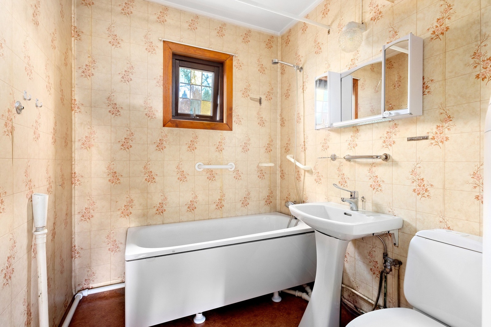 Badet er innredet med badekar, wc, servant med ett-greps blandebatteri, speil på vegg og delvis opplegg for vaskemaskin Galleribilde