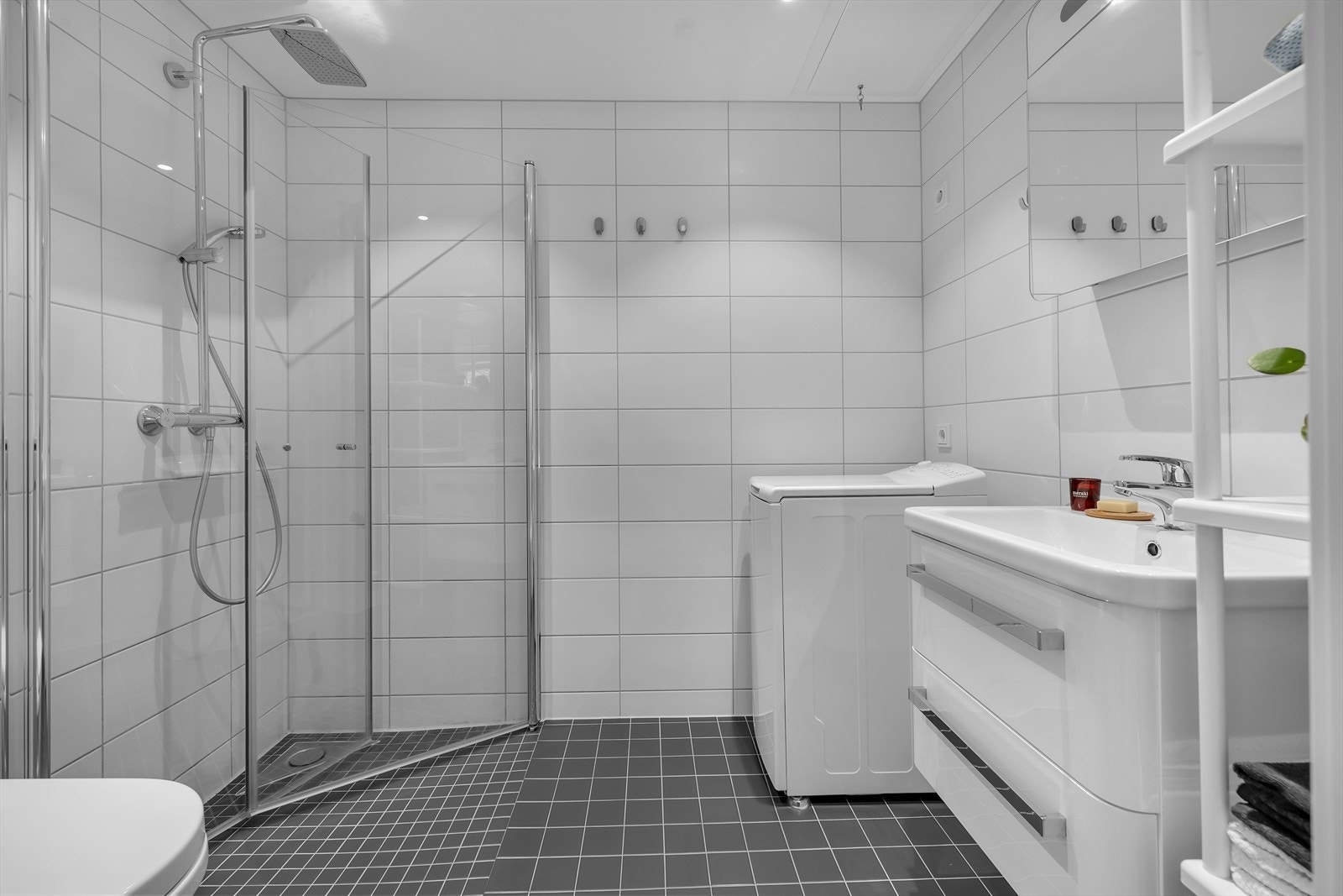 Komplett flislagt baderom med dusjvegger, vegghengt toalett, moderne innredninger og opplegg til vaskemaskin. Galleribilde