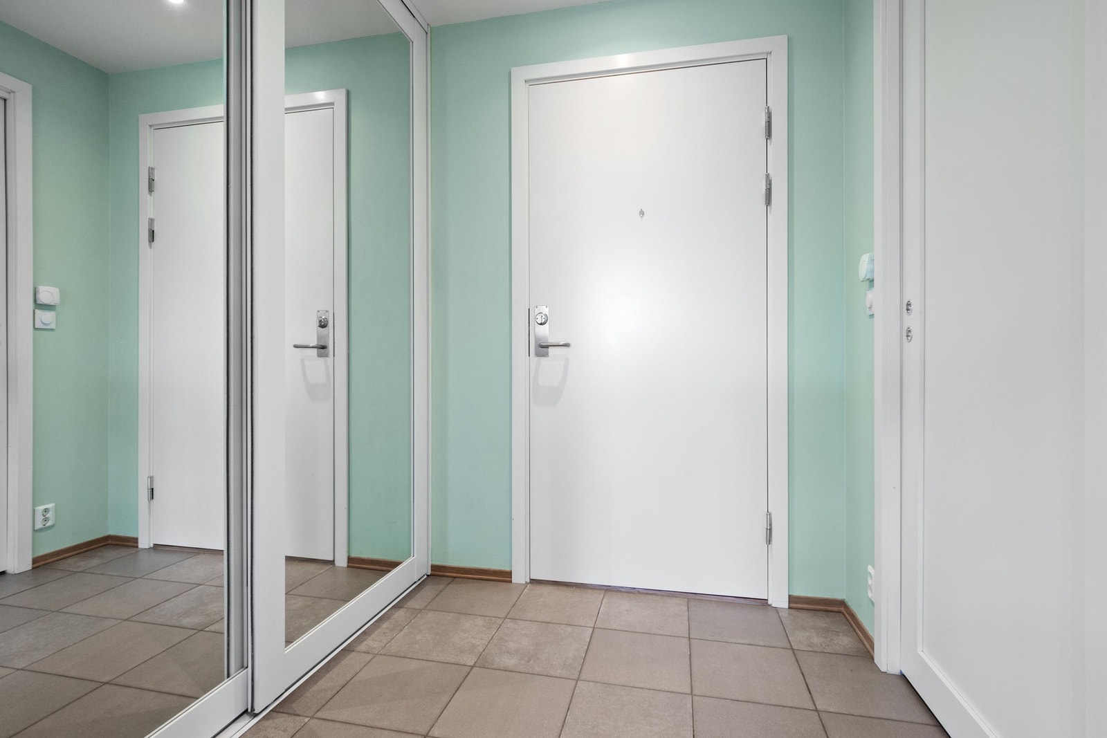 Entreen er innredet med en stor skyvedørsgarderobe med speil og hvite fronter, og har i tillegg skyvedør inn til en praktisk bod med skap. Galleribilde