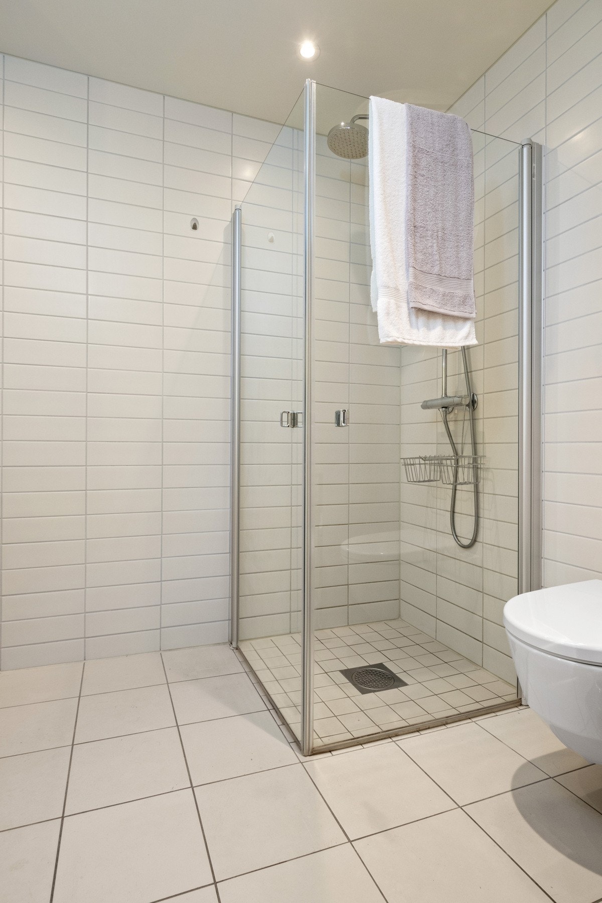 Badene har dusjhjørne med innfellbare glassdører, regnfallsdusj og hånddusj. Galleribilde