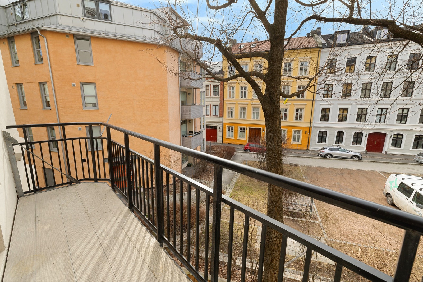 Stor, solrik balkong mot idyllisk og grønt gårdsrom. Galleribilde