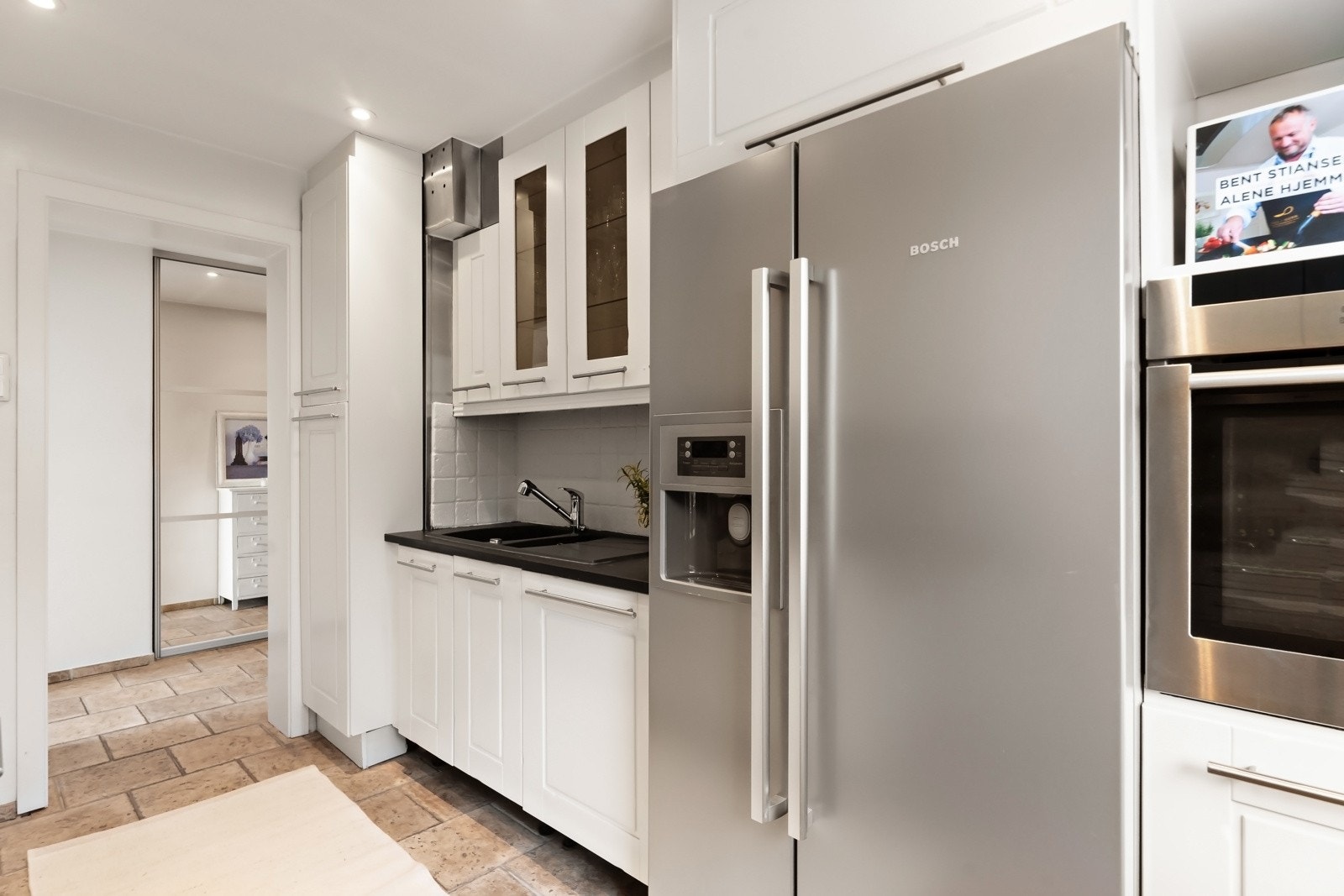 Leiligheten har en pen kjøkkeninnredning med hvitmalte, profilerte fronter og benkeplater i stein. Galleribilde