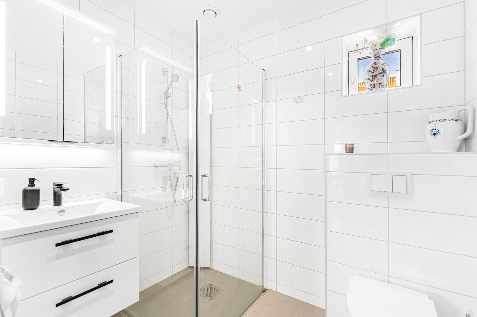 Badet er innredet med servant i baderomsmøblement, veggmontert toalett, dusjhjørne og har opplegg for vaskemaskin/tørketrommel. Galleribilde