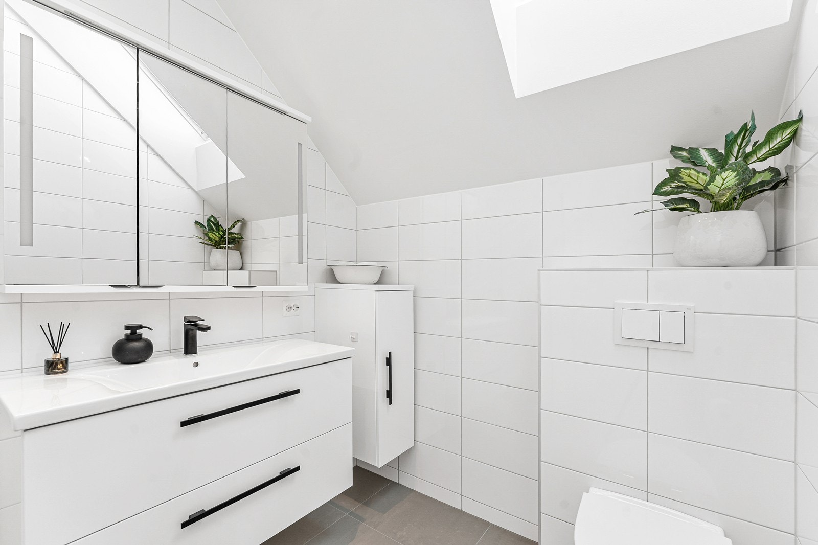 Badet er innredet med baderomsmøblement, veggmontert toalett og dusjhjørne. Galleribilde