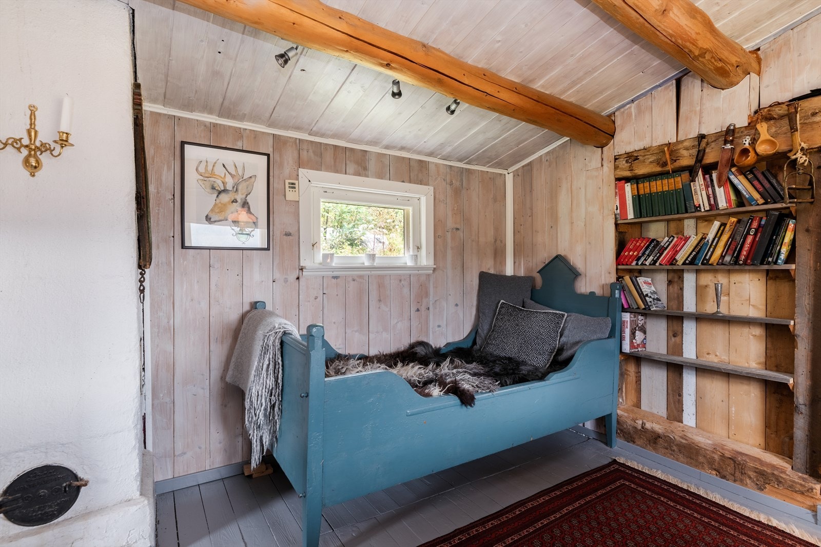 I andre enden av rommet er det en eldre seng, og det er tøffe hyller integrert i vegg mot kjøkken. Galleribilde