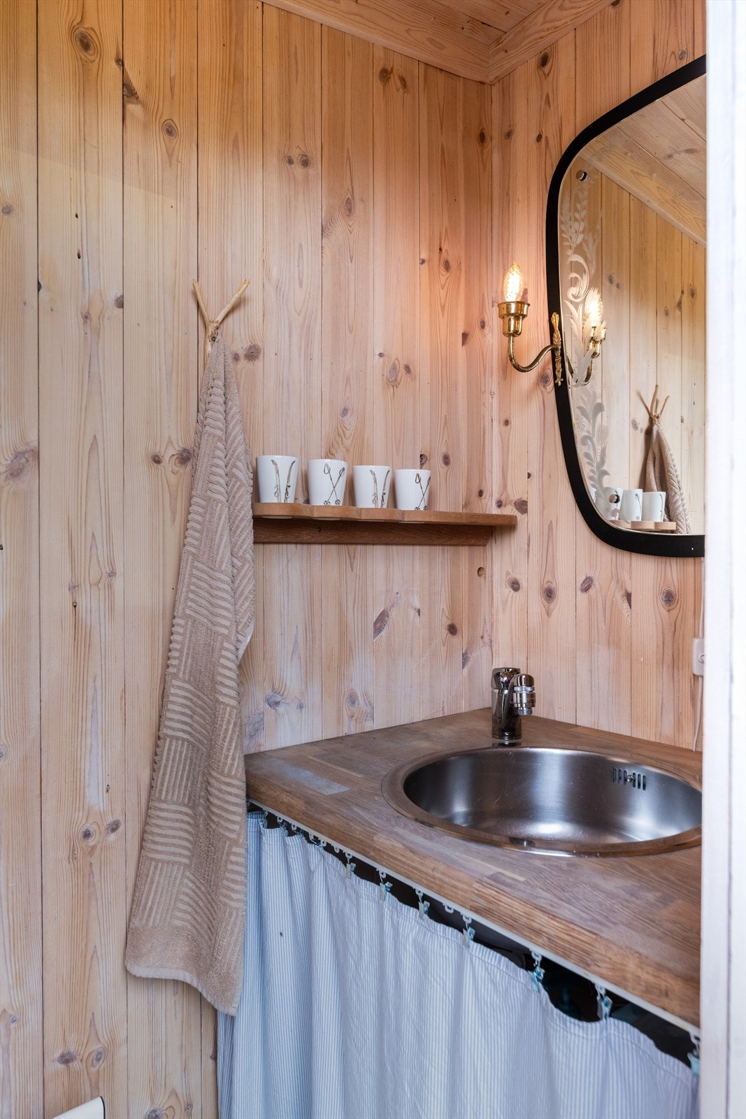 Enkelt baderomsmøblement med benkeplate med nedfelt servant hvor det er innlagt varmt og kaldt vann. Varmtvannstank på ca. 30 liter er plassert i benkeskap i rommet. Galleribilde