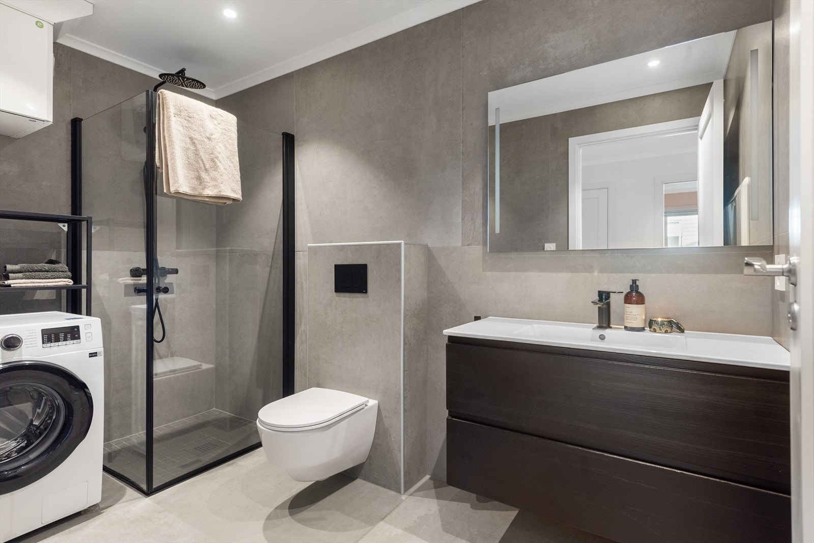 Badet i tilknytning til gangen har dusjhjørne, toalett, innredning med nedfelt servant og opplegg for vaskemaskin Galleribilde