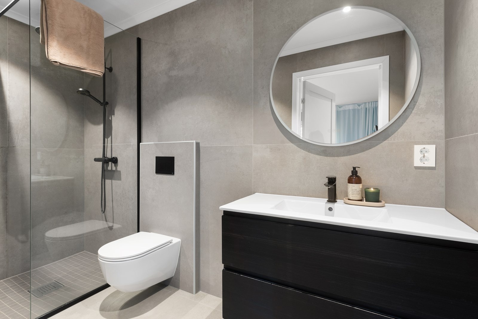 Det er direkte adkomst til et flislagt baderom med dusjhjørne, toalett og innredning med nedfelt servant Galleribilde