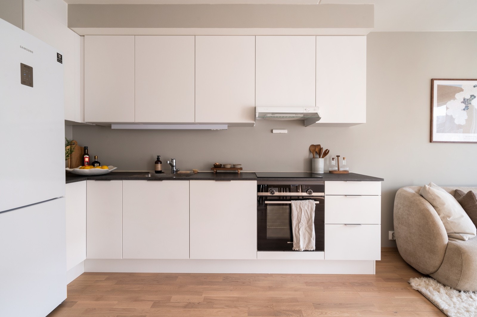 Underlimt rustfri oppvaskkum med ettgreps armatur gir en praktisk og stilren finish. Kjøkkenet er utstyrt med integrerte hvitevarer, inkludert oppvaskmaskin og stekeovn med induksjonstopp Galleribilde