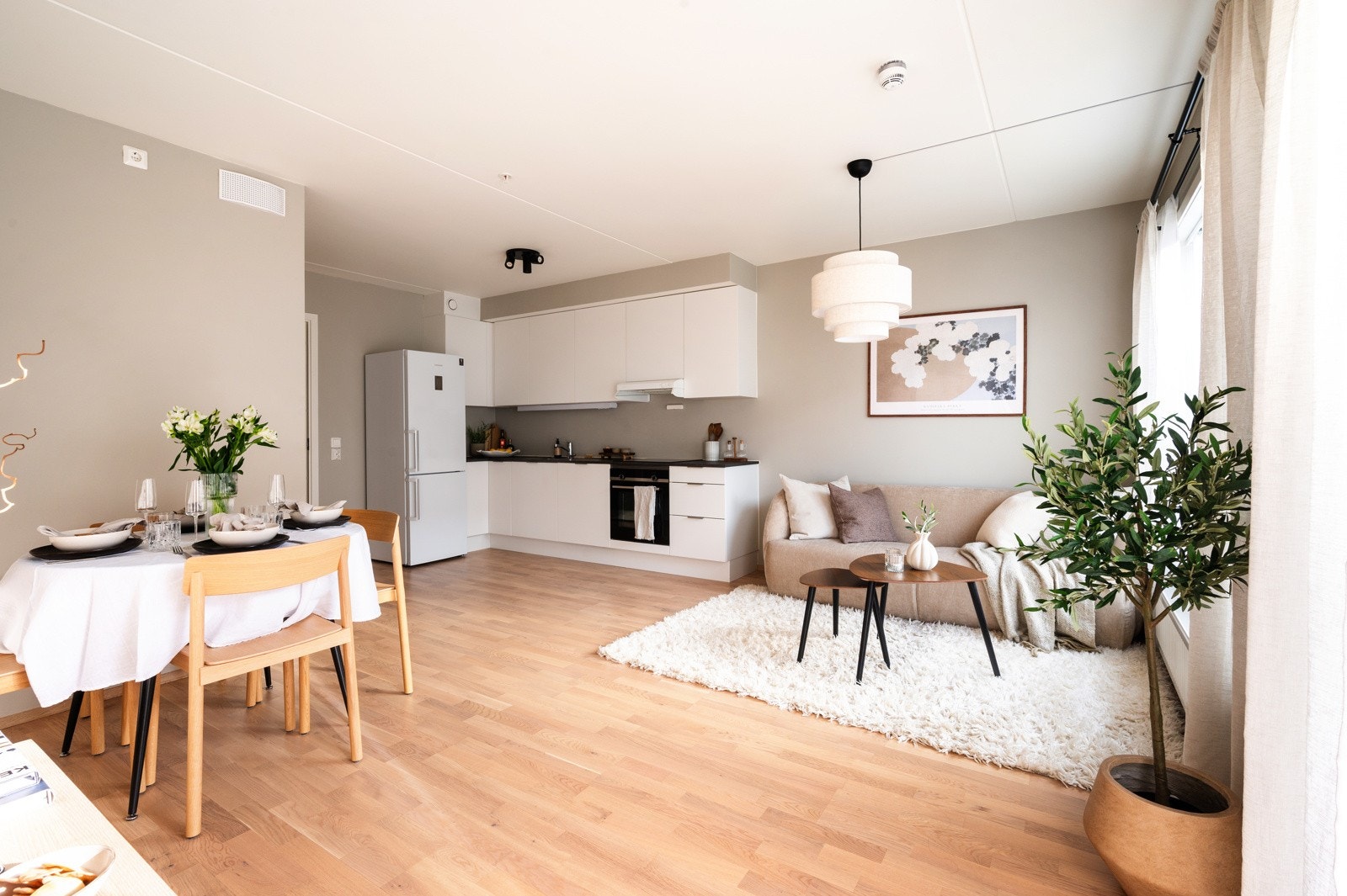 Leilighetens kjøkken ligger i åpen løsning mot stuen og har en moderne, stilren innredning, med hvite, glatte skapfronter og laminat benkeplate Galleribilde