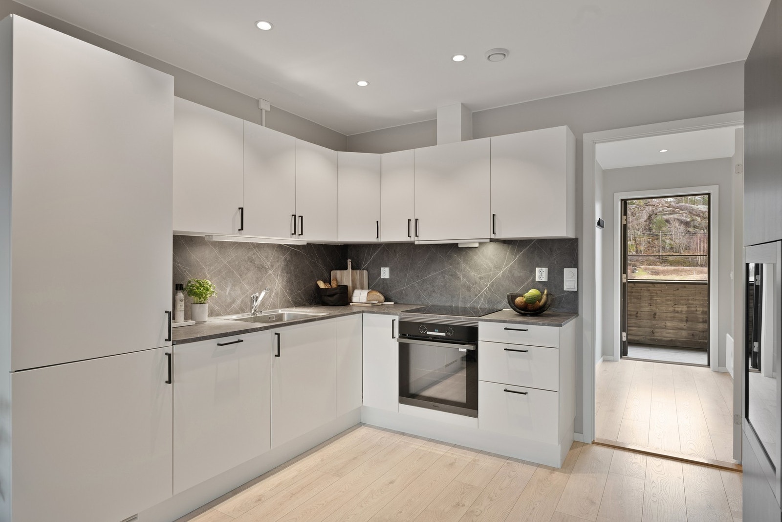 Et lyst og tidløst kjøkken med slette fronter. Det er god plass til diverse kjøkkenartikler i skap og skuffer. Galleribilde