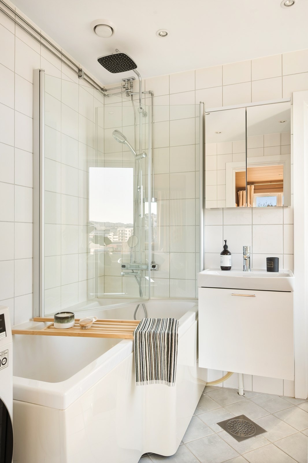 Badet inneholder baderomsinnredning med benkeskap, veggskap med belysning- og speilfronter, høyskap, dusj i badekar og servant. Galleribilde