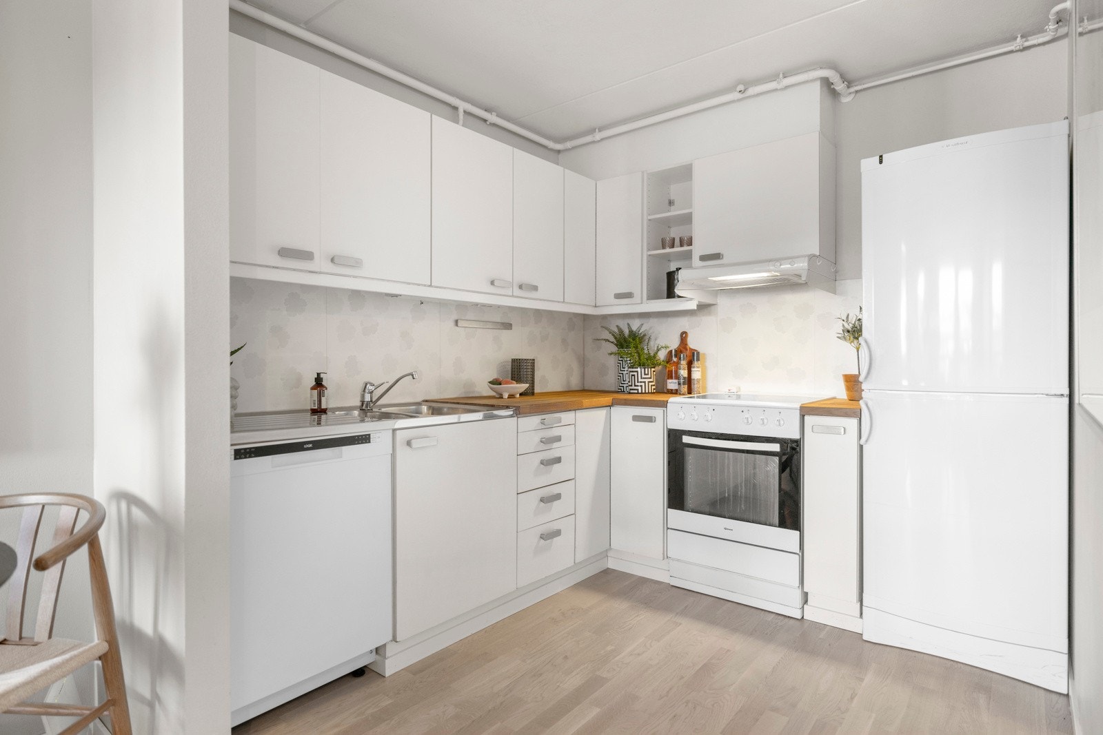 Kjøkkenet har et lyst kjøkken med glatt laminatinnredning, heltre benkeplate, ventilatorvifte og nedfelt kum i rustfritt stål. Galleribilde