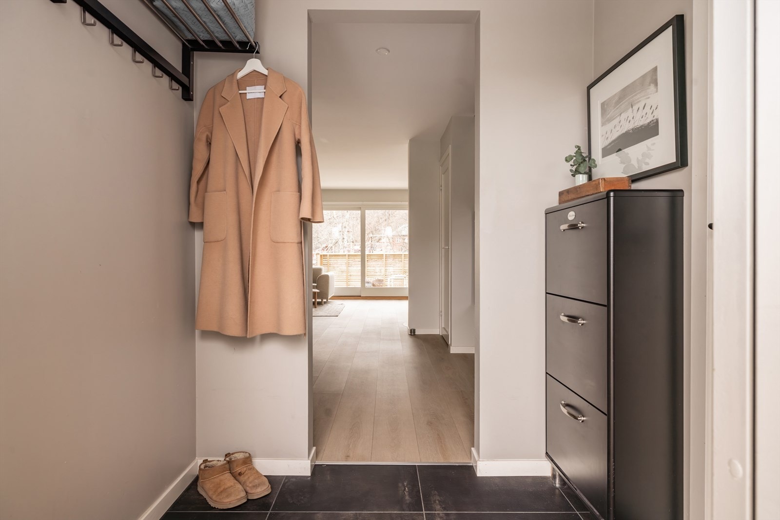 Lys og innbydende entré med flislagt gulv og gulvvarme. Mulighet for oppheng av jakker på knagger langs veggen, samt plassering av en kommode på motsatt vegg. Galleribilde