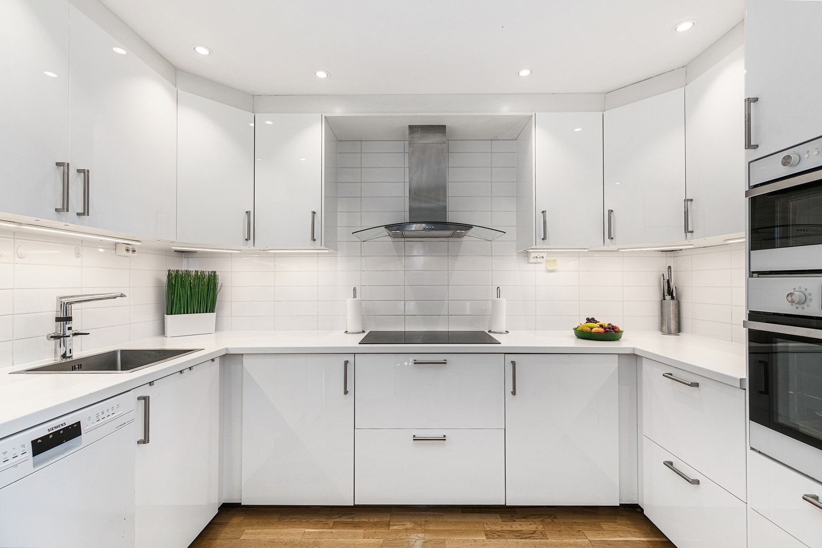 Delikat kjøkkeninnredning med laminert innredning glatte fronter i høyglans utførelse med god utnyttelse i hjørne av rommet. Galleribilde