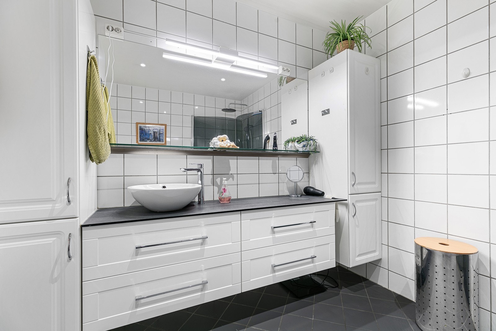 Romslig baderomsinnredning med hvite profilerte fronter, stort speil og en moderne bolleservant. Galleribilde
