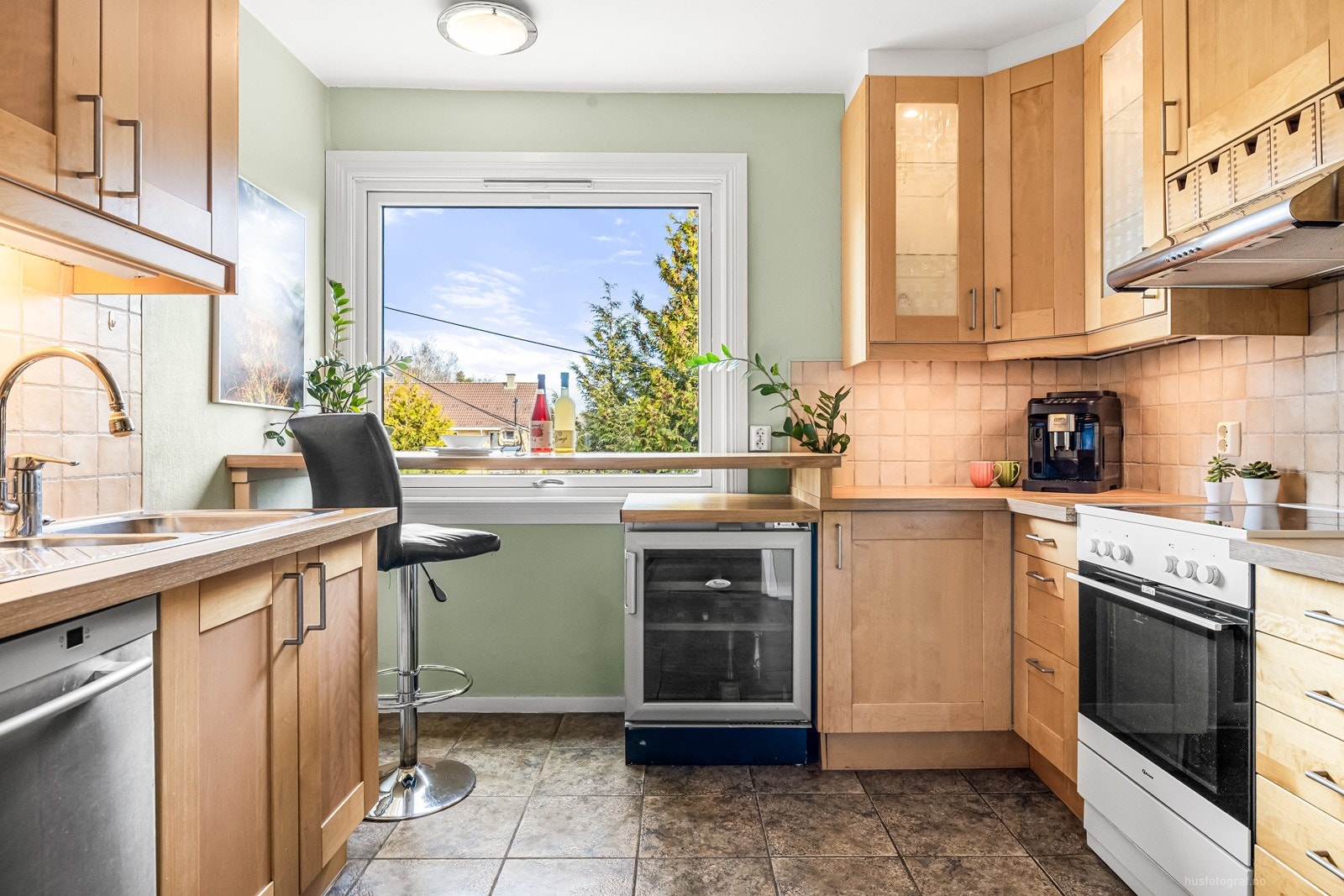 Kjøkkenet har glatt innredning, laminat benkeplate, og fliser mellom benk og overskap. Galleribilde