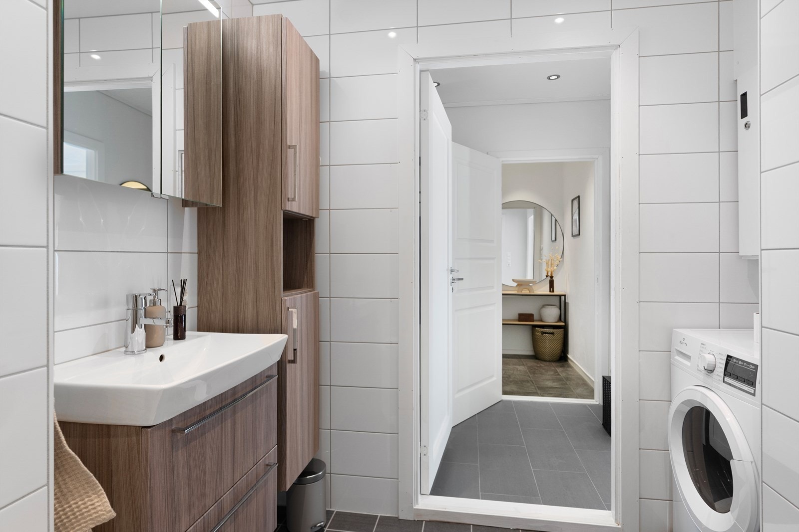 Badet er innredet med vegghengt toalett, dusjhjørne m/vegger, opplegg for vaskemaskin og servant med innredning, speil og belysning. Galleribilde