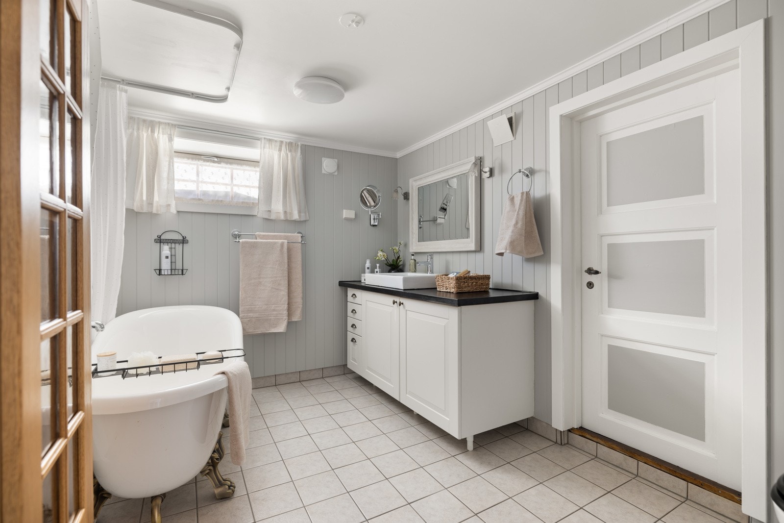 Sjarmerende flislagt bad med bergvarmeoppvarming i gulv. Badet ble etablert i 2010. Innredning med profilerte fronter og heldekkende servant. Speil på vegg over servanten. Galleribilde