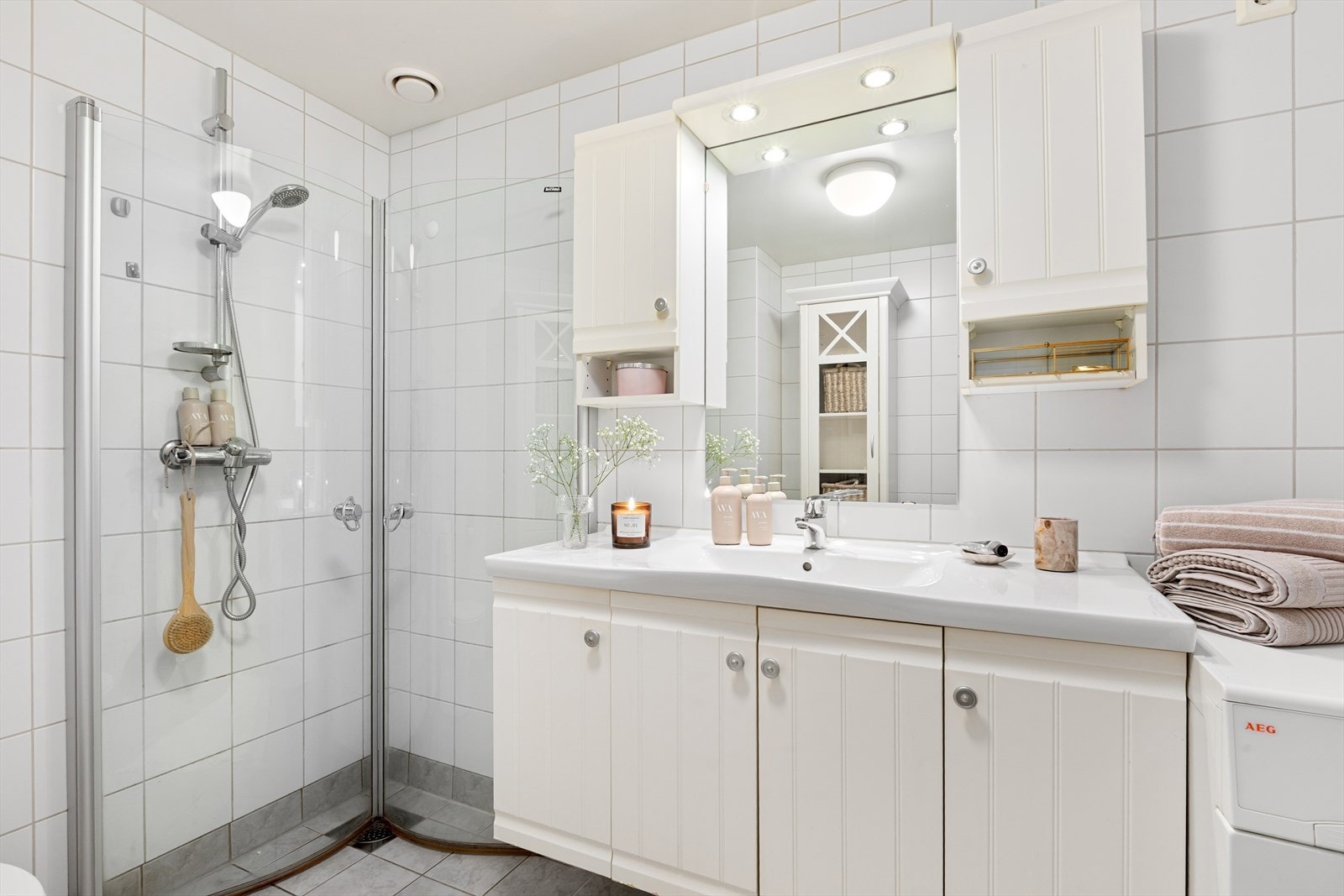 Badet er utstyrt med servant med underskap, veggskap og speil med lys, dusjnisje med innfellbare dører, toalett samt opplegg for vaskemaskin Galleribilde