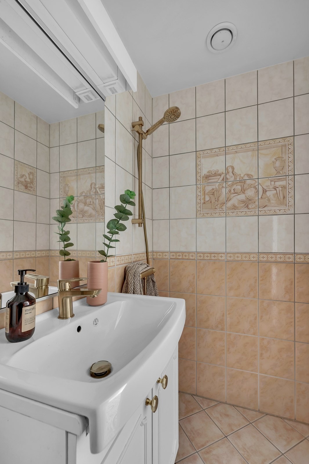 Baderommet er innredet med gulvstående toalett, servant nedfelt i innredning og dusjhjørne. Naturlig ventilasjon. Galleribilde