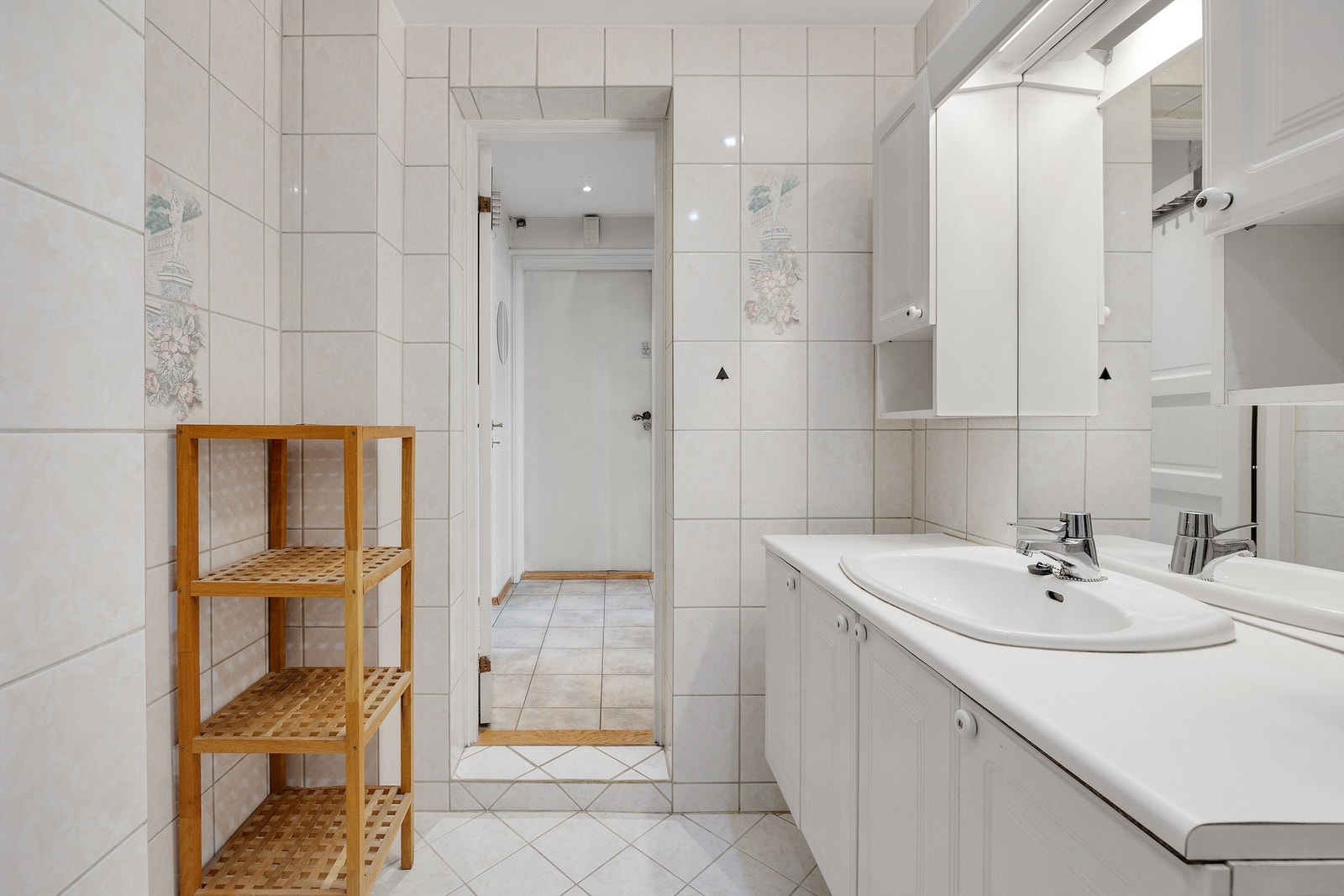 Badet er innredet med servantinnredning, nedfelt servant med ett-greps armatur, speil, veggmontert dusjarmatur og gulvstående toalett. Galleribilde