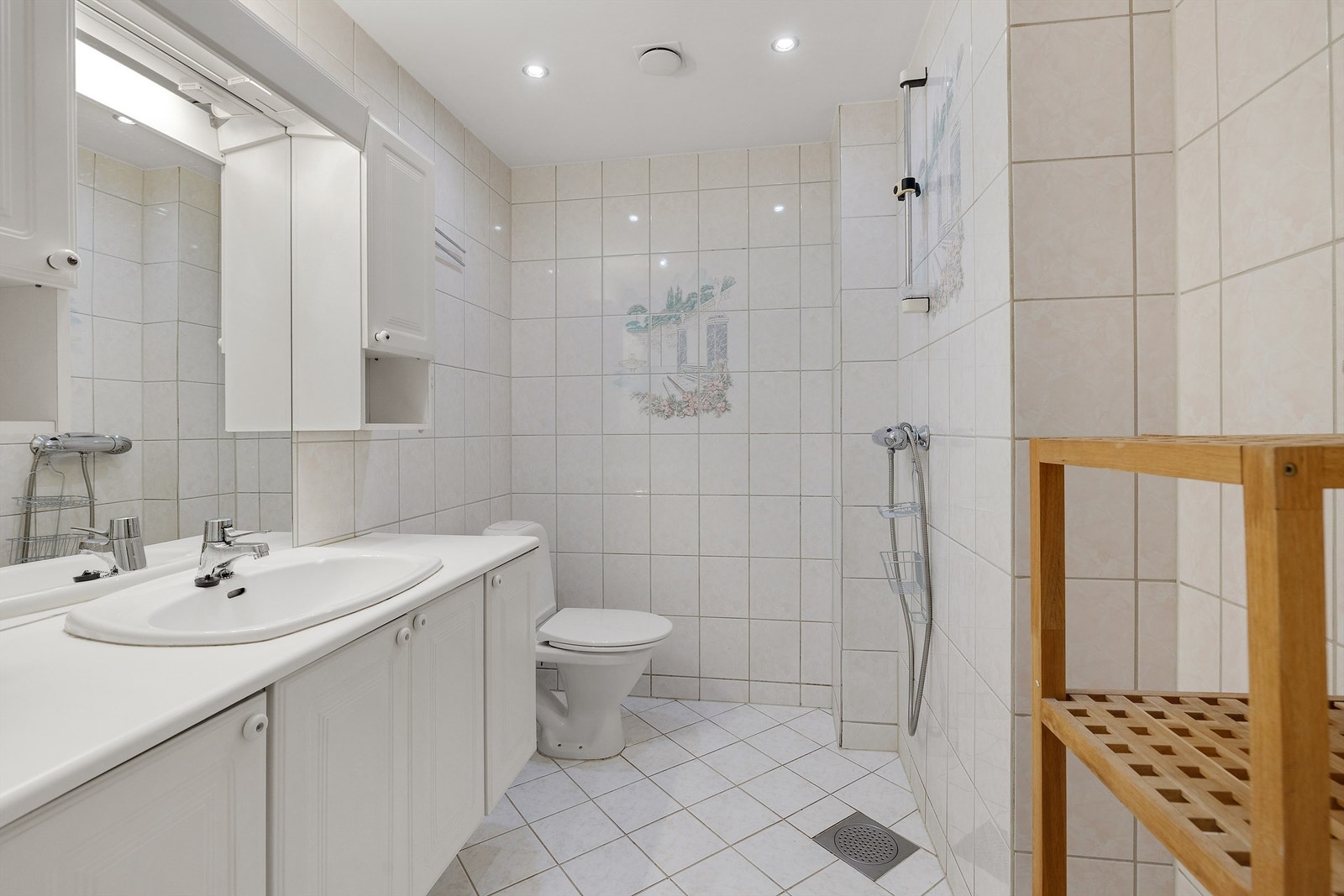 Lyst flislagt baderom fra ukjent årstall med gulvvarme og downlights i himling. Galleribilde