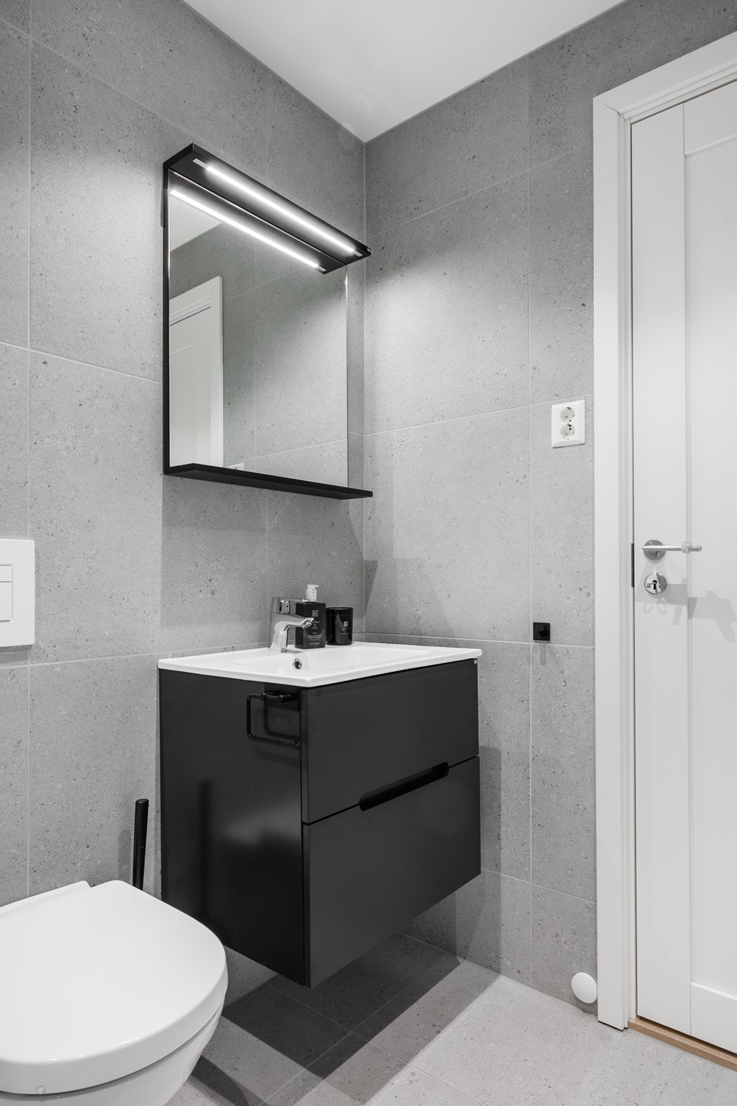 Innredningen består av dusjhjørne med glassdører og regnfallsdusj, toalett, servantskap og speil med lys. Galleribilde