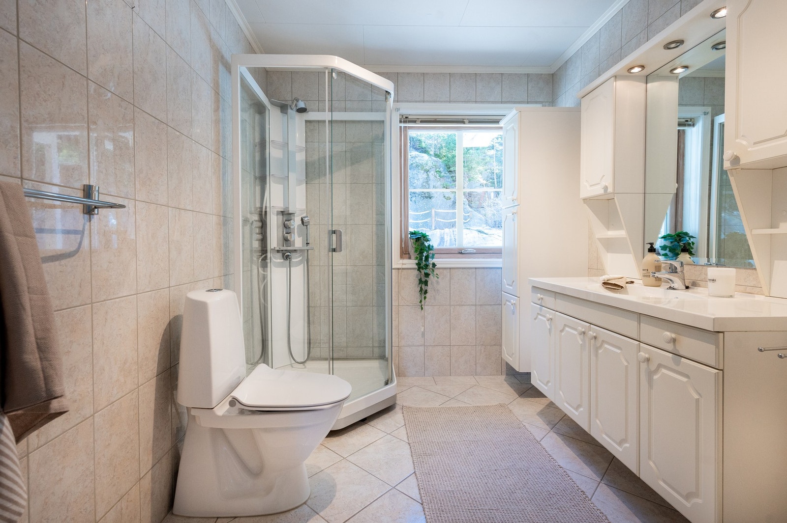 Romslig og lyst bad innredet med servantinnredning med speil, skaper, dusjkabinett og toalett. Gulvvarme. Galleribilde