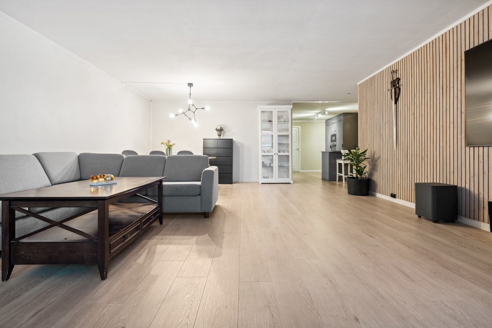 Stuen er utført med et lyst 1-stavs laminatgulv, hvitmalte overflater og en spilevegg som gir et moderne uttrykk Galleribilde