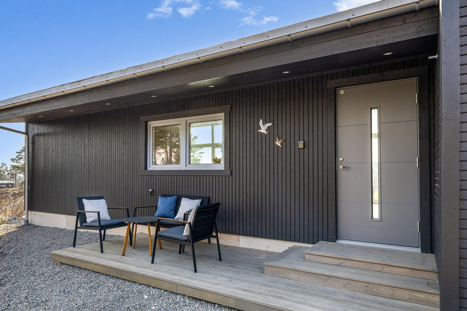 BAKSIDE MED STIL: Fra inngangspartiet ser du tvers gjennom hytta og ut mot sjøen. Her er det også anlagt en liten terrasse for morgensolen. Galleribilde