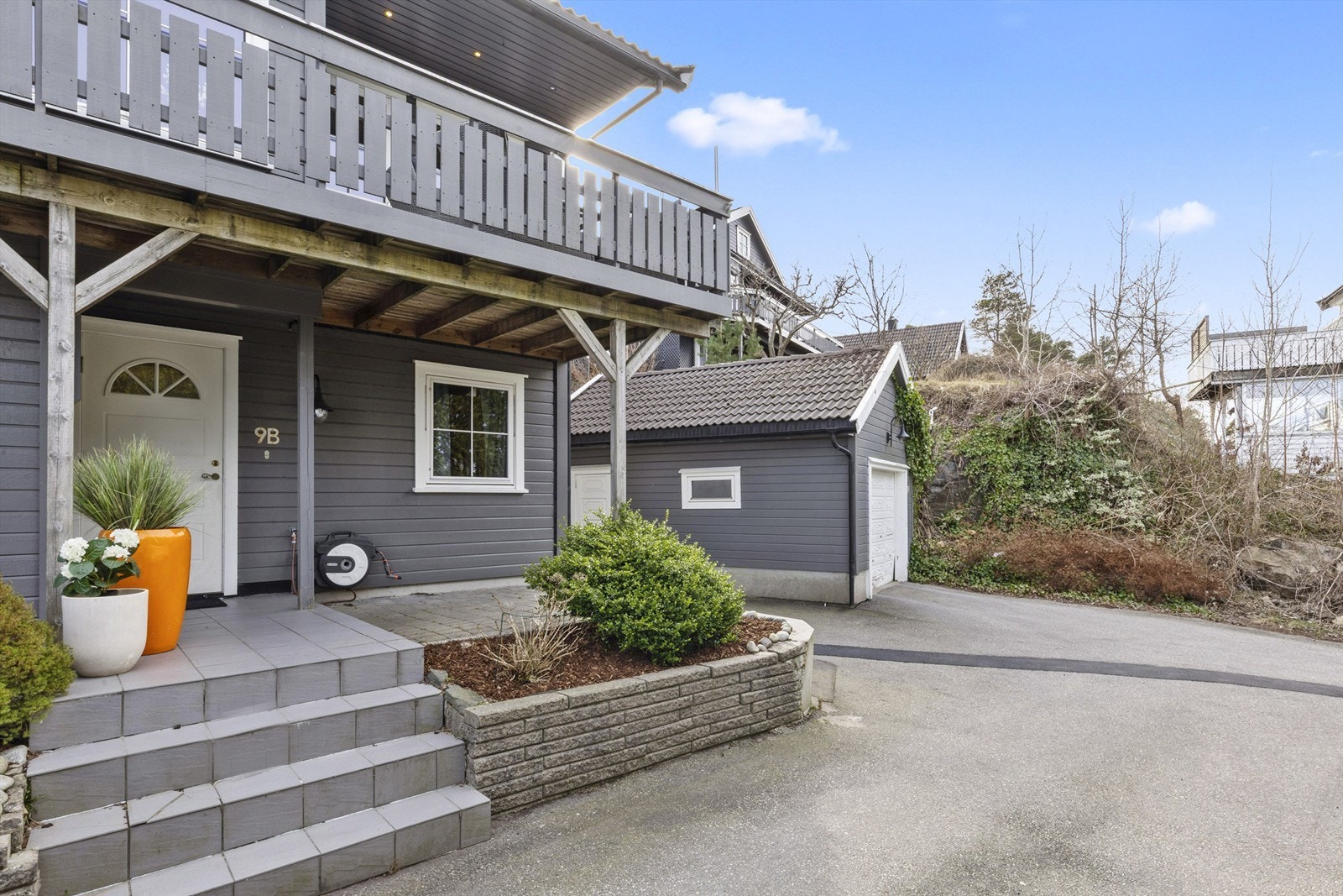 Hyggelig inngangsparti opparbeidet med fliser, belegningsstein og blomsterbed. Galleribilde