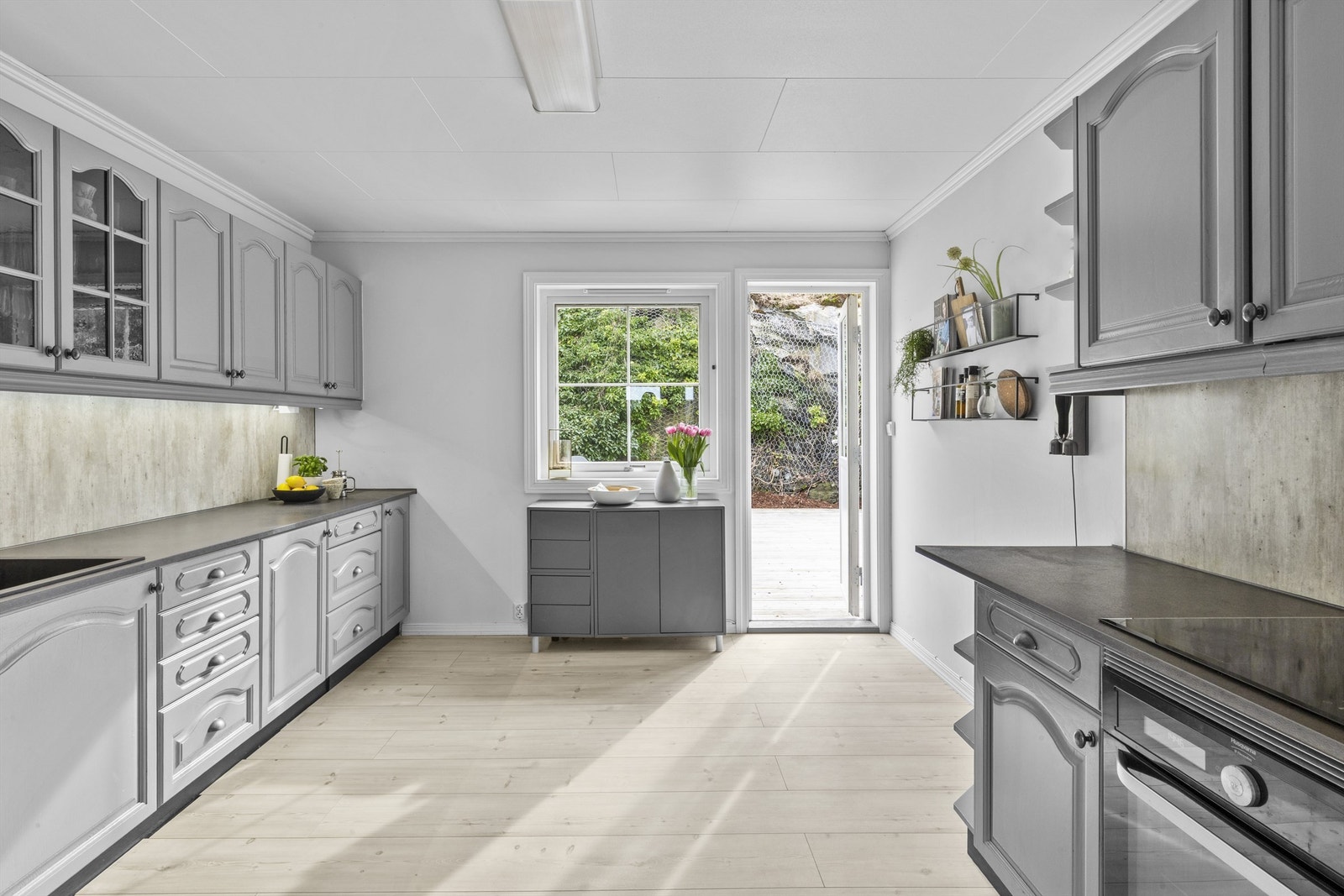 Kjøkken av god størrelse med innredning fra byggeår. Det er plass til en liten spisekrok, og videre er det utgang til terrassen på baksiden av huset. Galleribilde