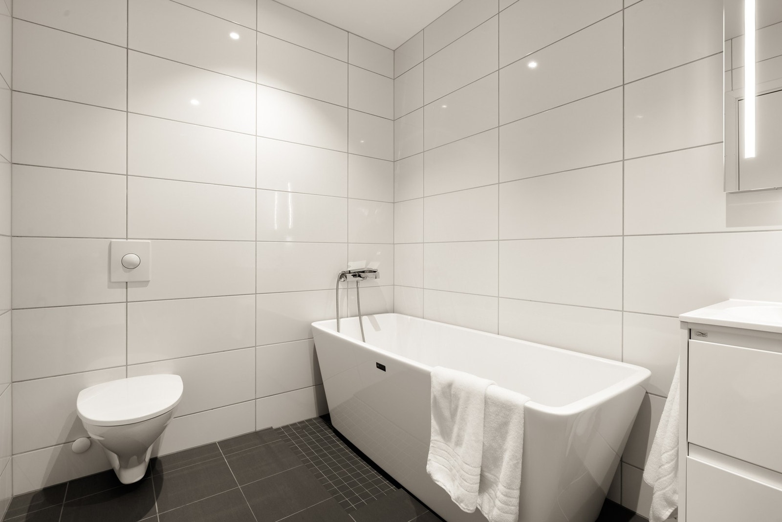 Badet i 1.etg inneholder badekar, vegghengt toalett og baderomsinnredning. Galleribilde