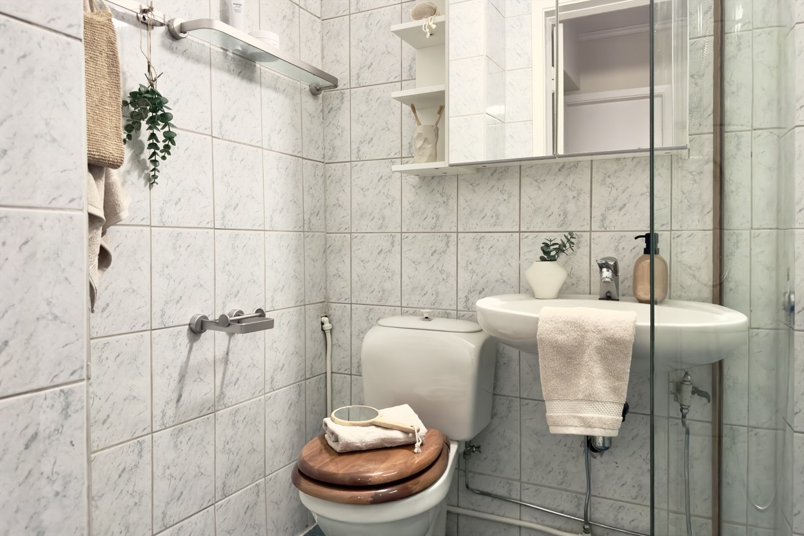 Badet er utstyrt med toalett, vask med overskap og dusjhjørne. Galleribilde