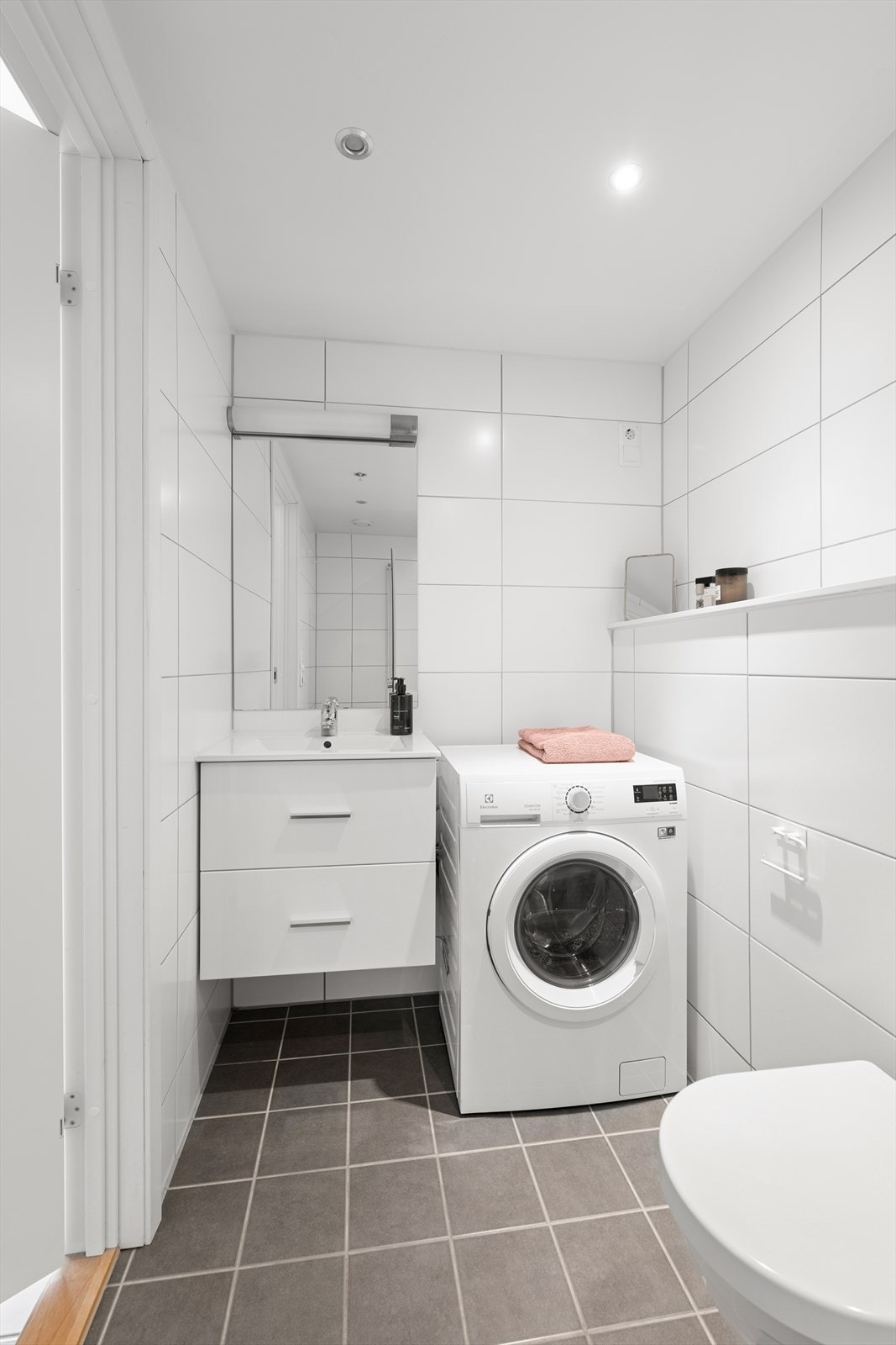 Heldekkende servant på underskap med høyglansfolierte fronter, speil, lysarmatur og veggmontert klosett Galleribilde