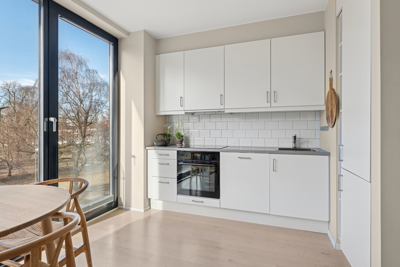 Lyst og stilrent Norema-kjøkken med glatte folierte fronter, laminat benkeplate med nedfelt kum i rustfritt stål Galleribilde