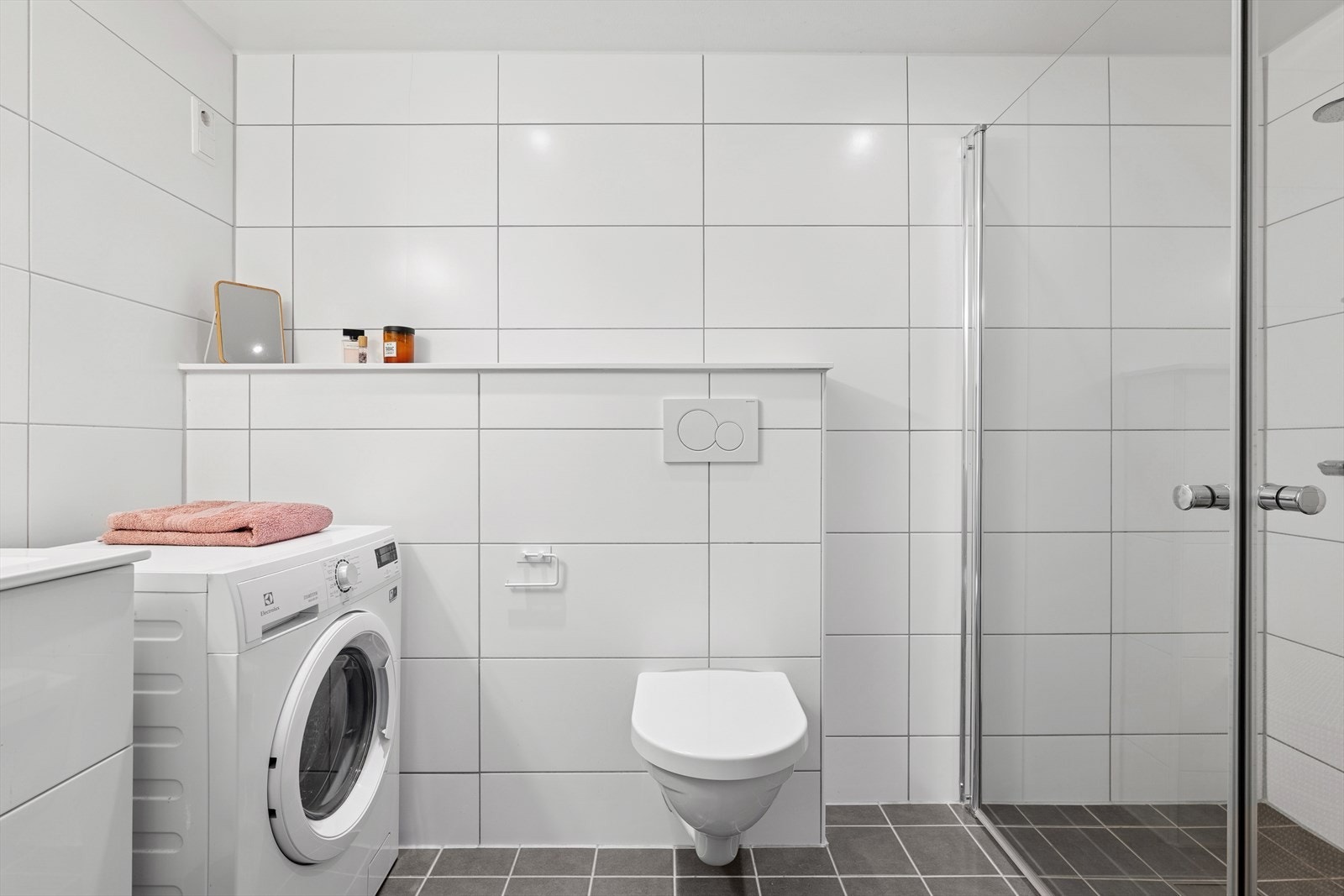 Lyst og moderne bad med fliser, downlights, varmekabler og opplegg for vaskemaskin Galleribilde